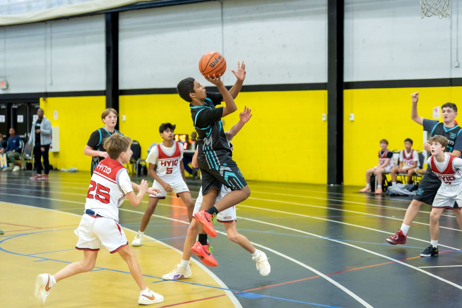 Young basketball player drives to the hoop during a youth league game in an indoor gymnasium.