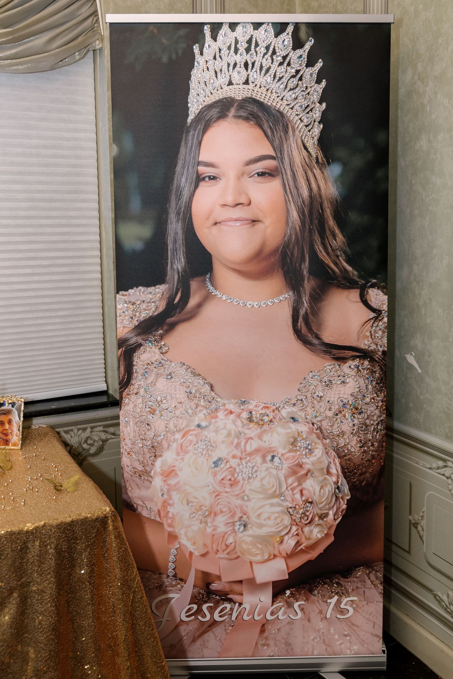 A Quinceañera celebration display banner showing someone wearing a sparkly crown and pink embellished gown.