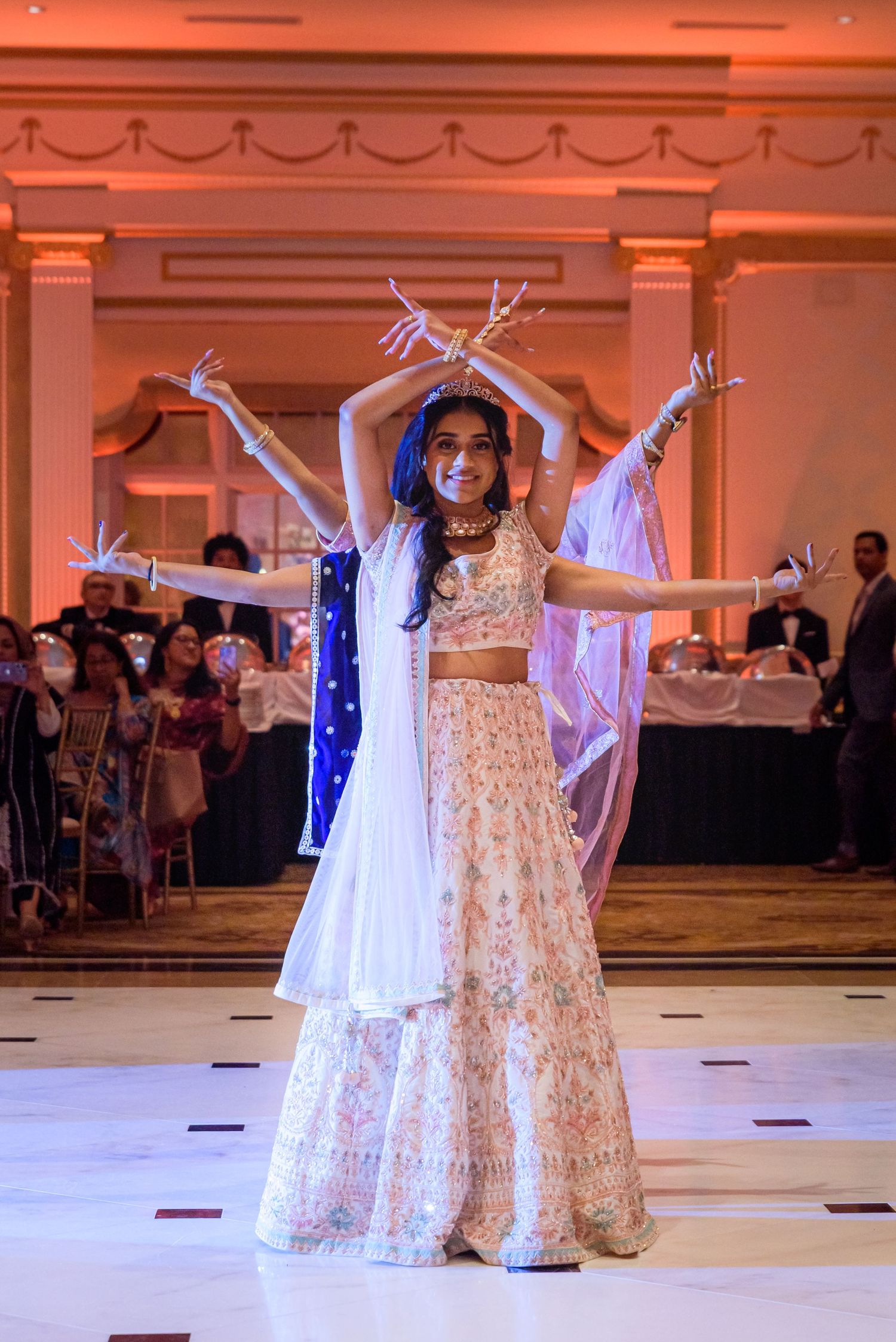 Dancers in flowing white gowns performing a choreographed routine at a wedding reception.