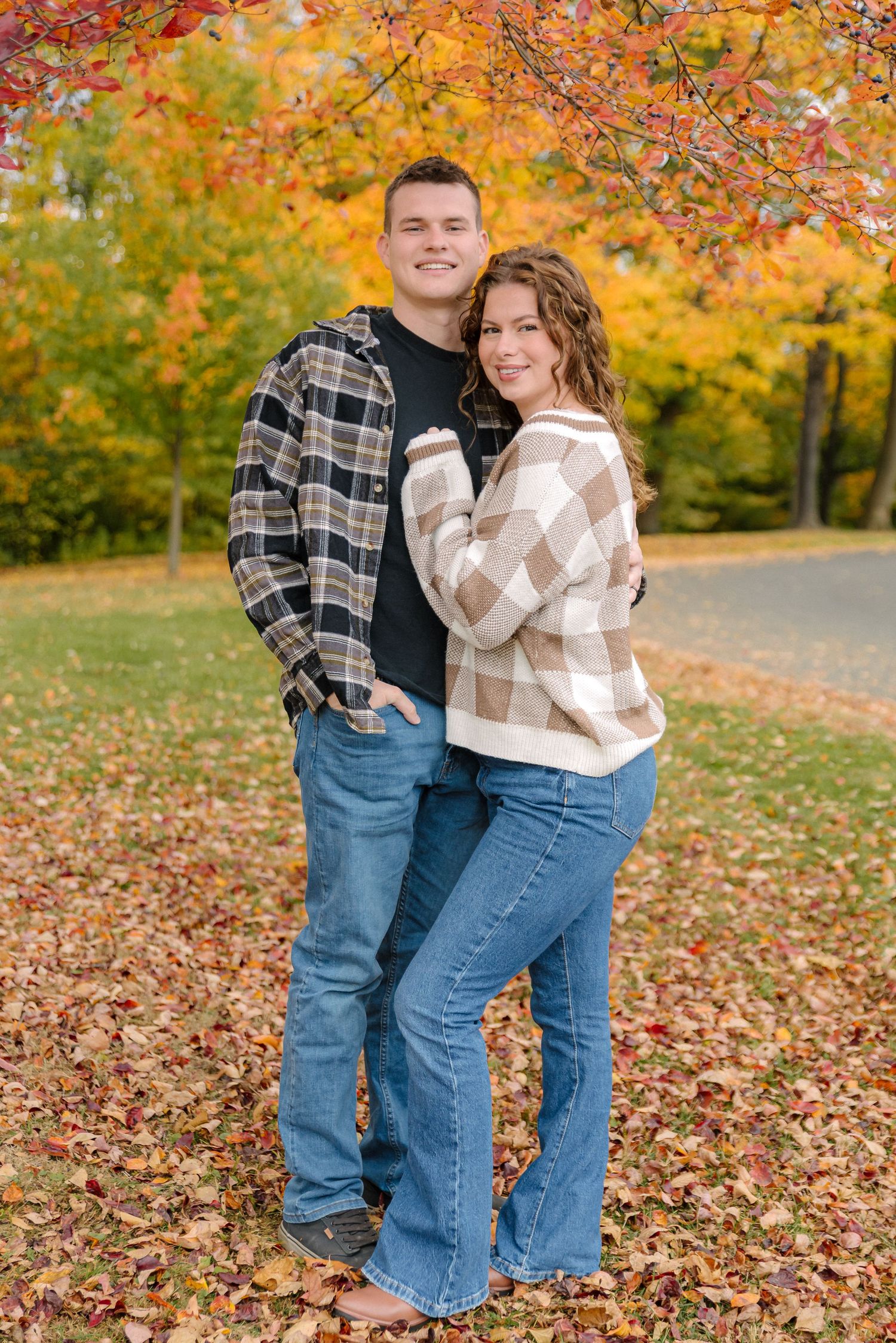 Autumn couples photoshoot with colorful fall foliage in the background.