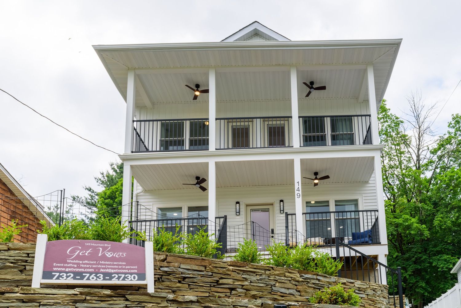 White colonial style house exterior with stone accents and covered porch.