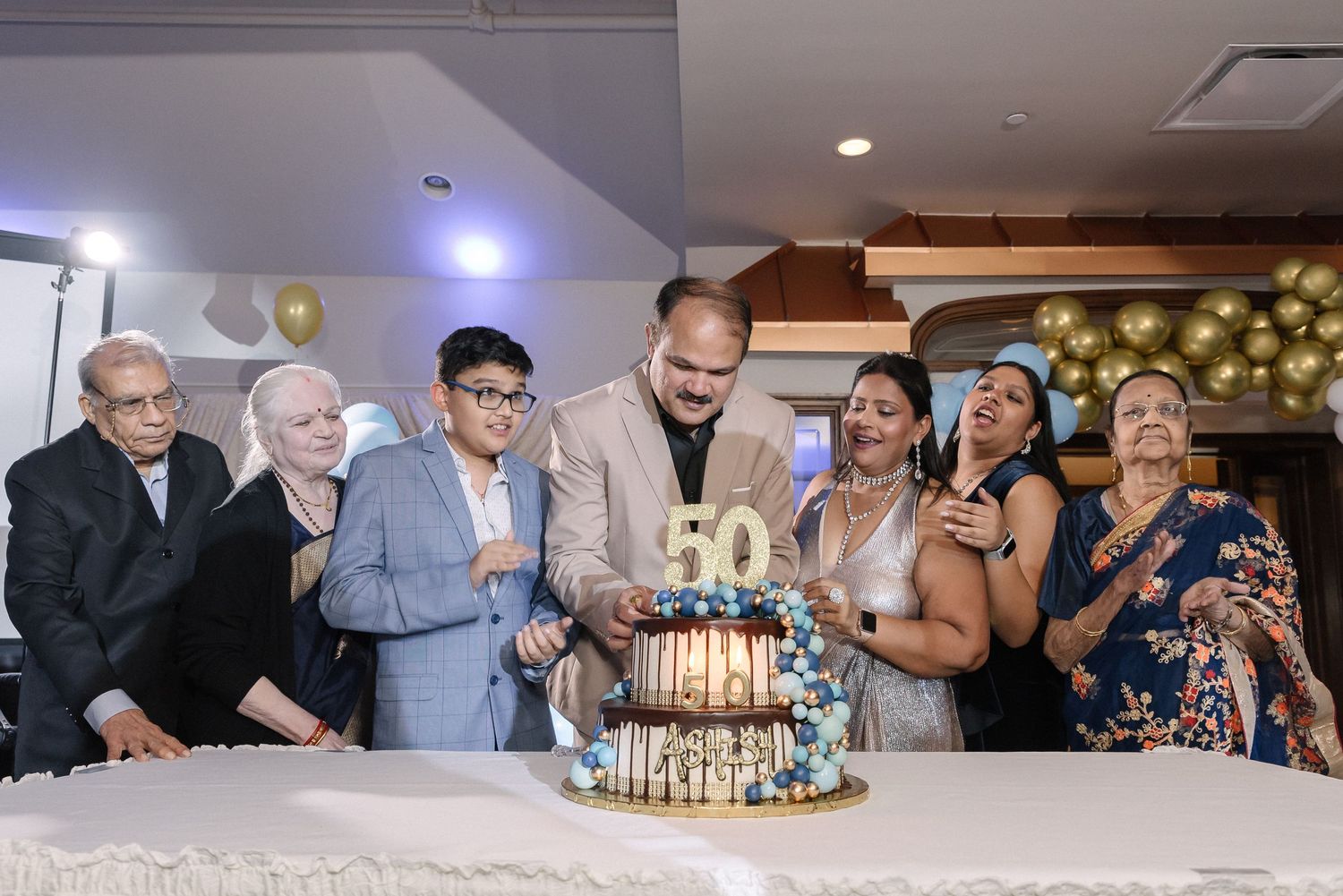 Guests enjoying a festive celebration with gold balloon decorations and party ambiance.