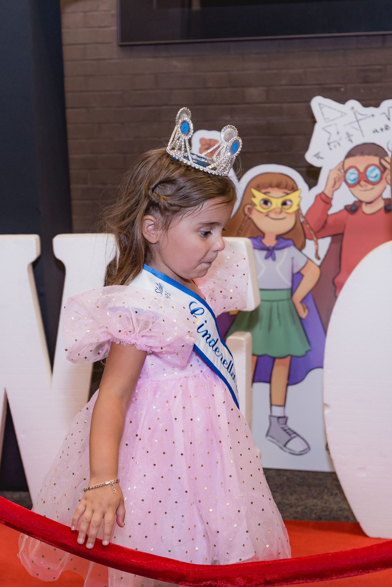 Young attendees in formal wear pose near cartoon character decorations at event.