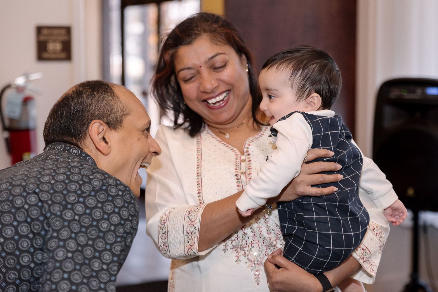 Candid moments of guests interacting at a formal indoor celebration.