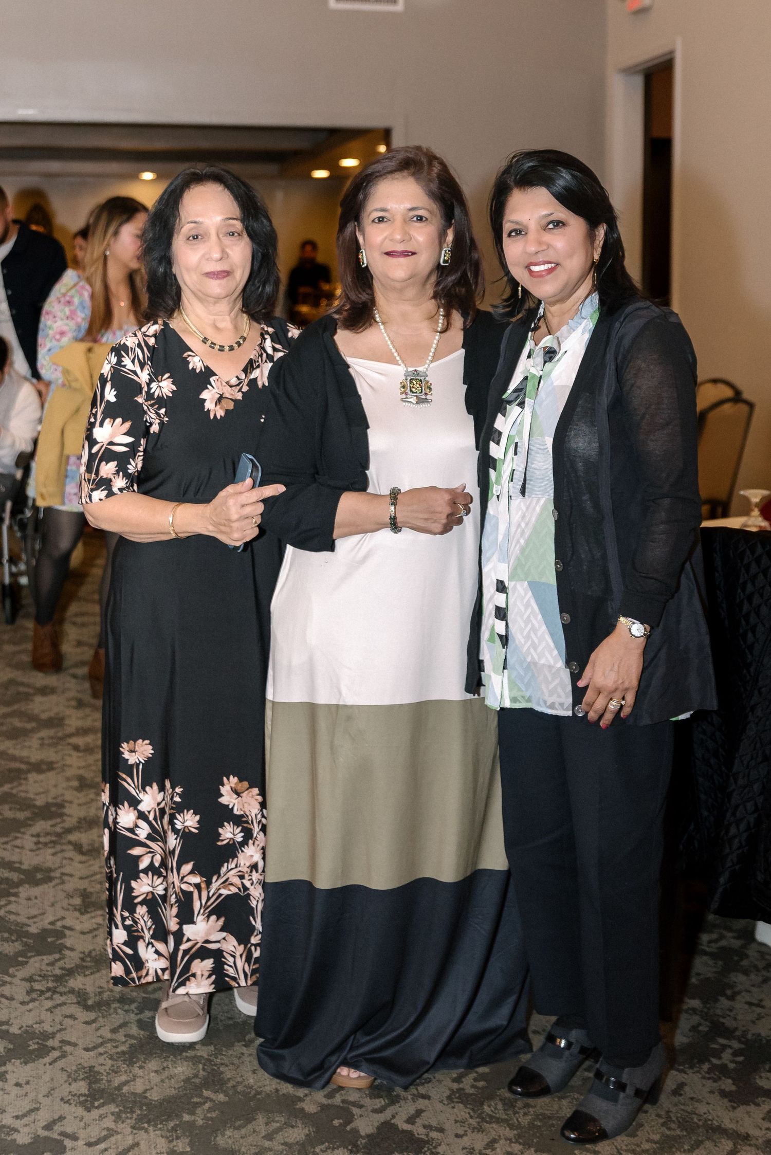 Group of guests in formal black attire posing together at an indoor celebration.