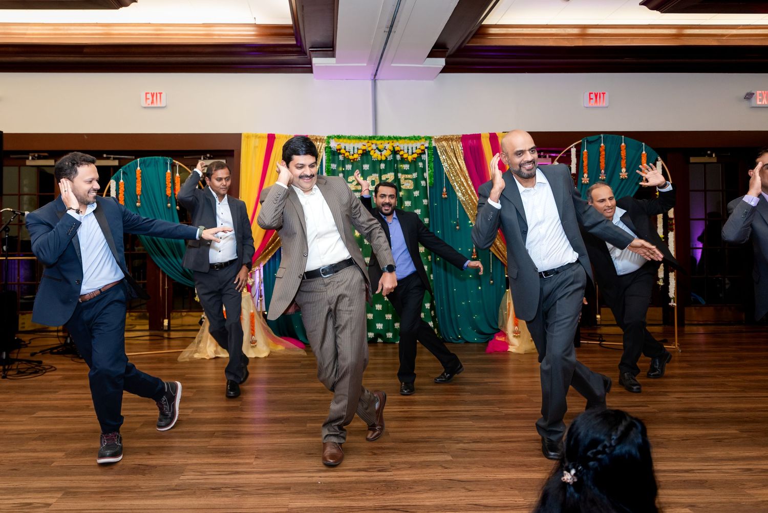 Group of men dancing energetically on a wooden floor during a celebration.