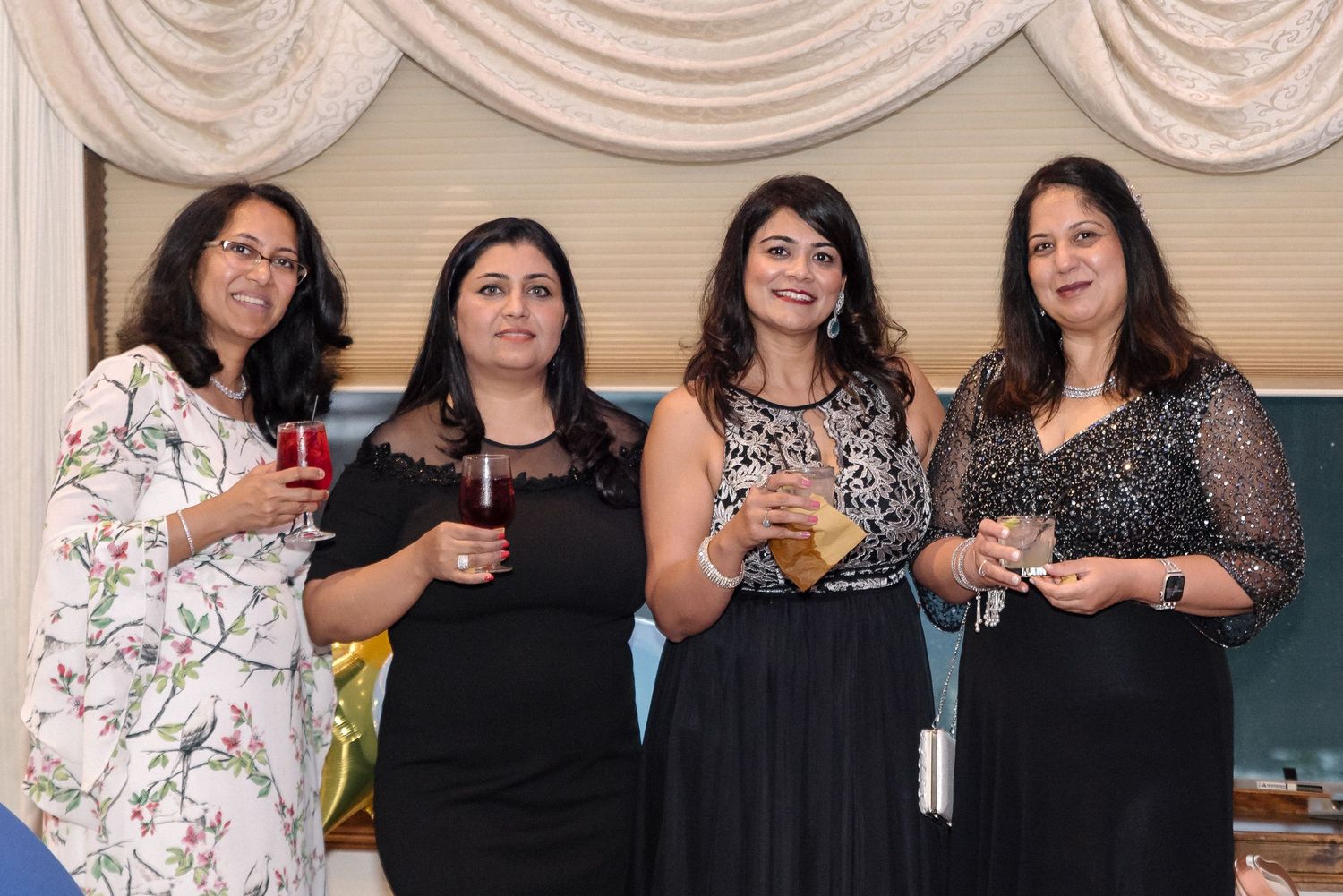Group of friends enjoying drinks and conversation at an elegant party with draped decor.