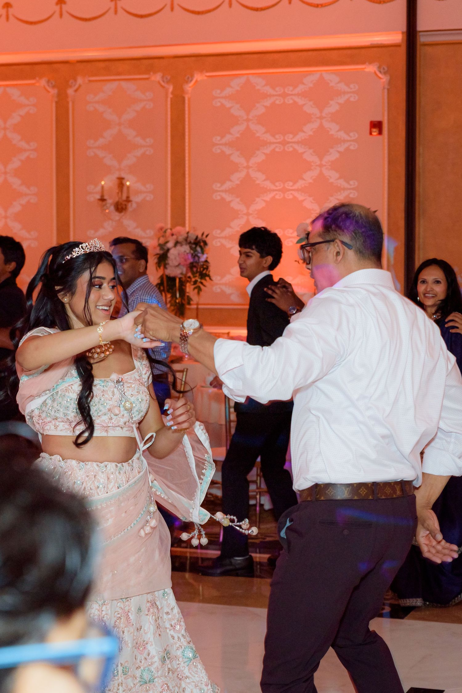 Wedding reception dance floor filled with guests dancing under ambient lighting.