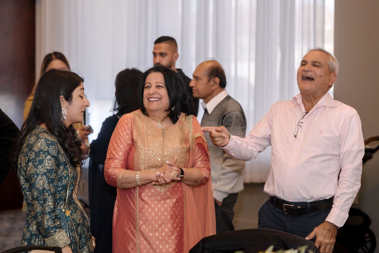 Group of attendees laughing and socializing at an indoor celebration.