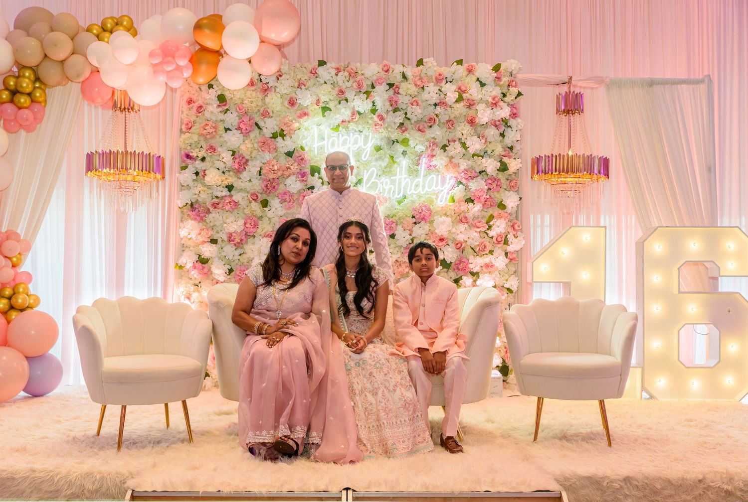 Elegant wedding venue decorated with pink floral arrangements, draped fabric, and crystal chandeliers.