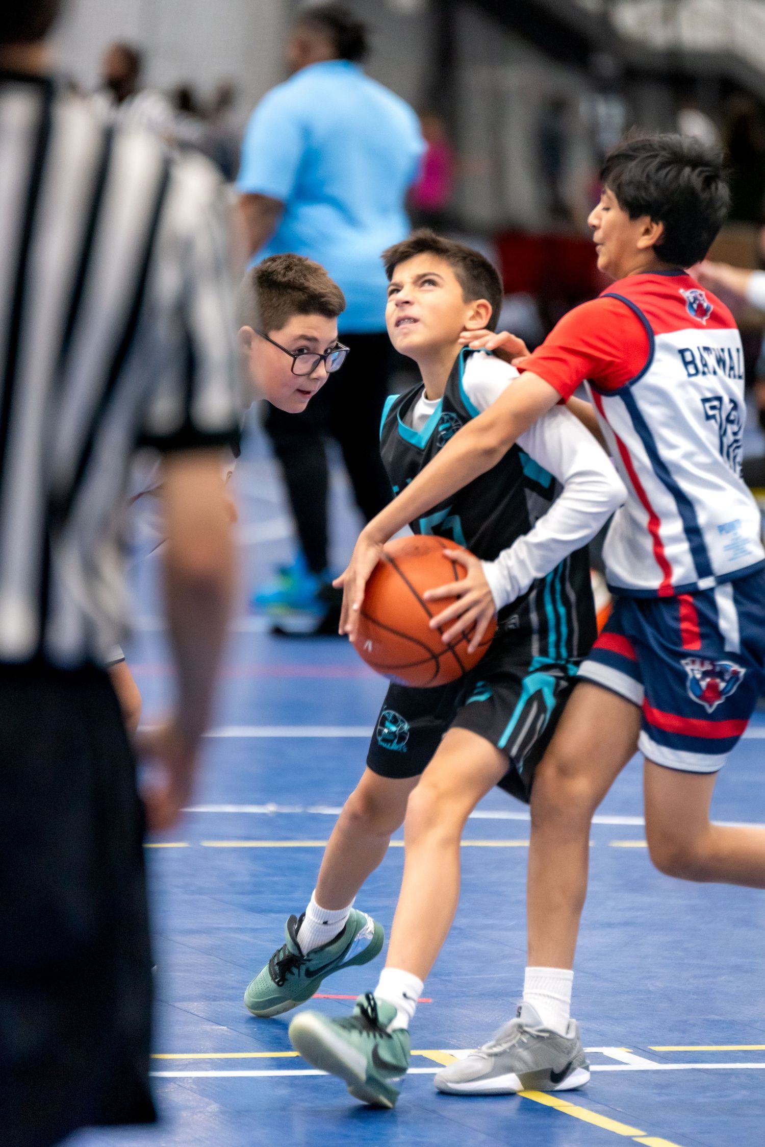 Two young basketball players battle for possession during an intense youth league indoor game.