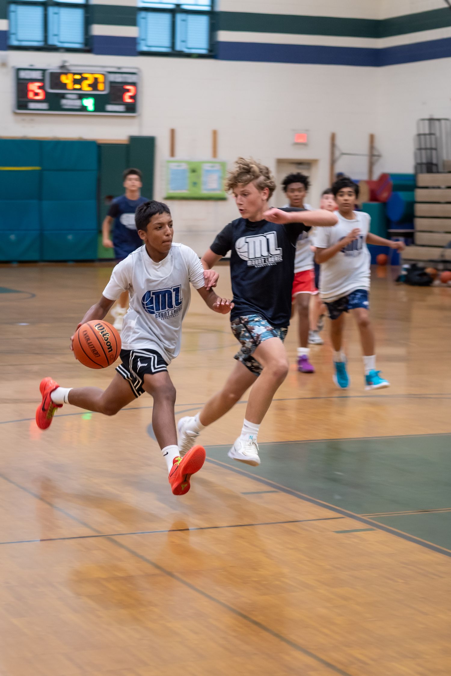 Basketball players leap and dive across a gymnasium floor during an intense practice session.