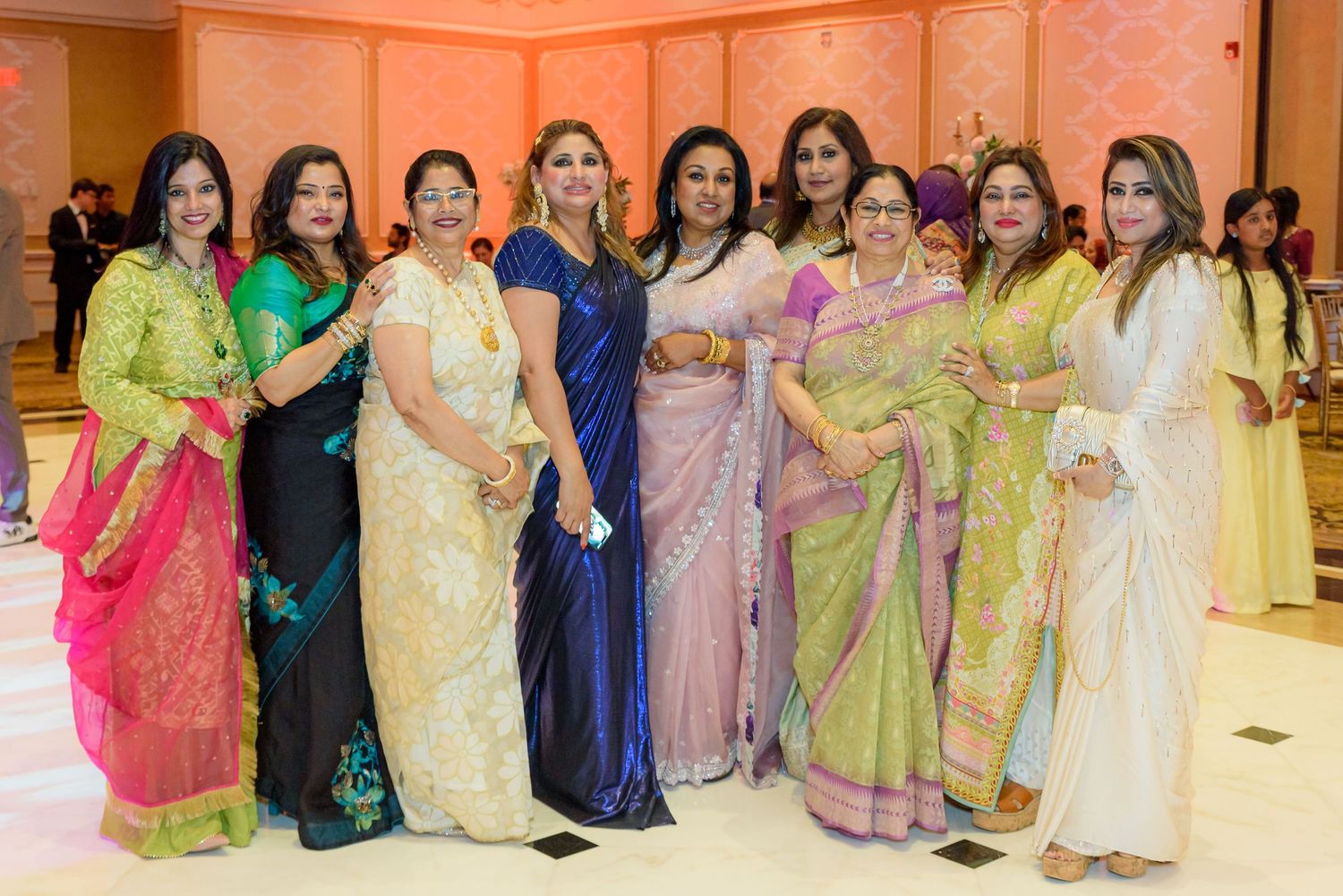 Wedding reception guests in colorful traditional attire posing for a group photo.