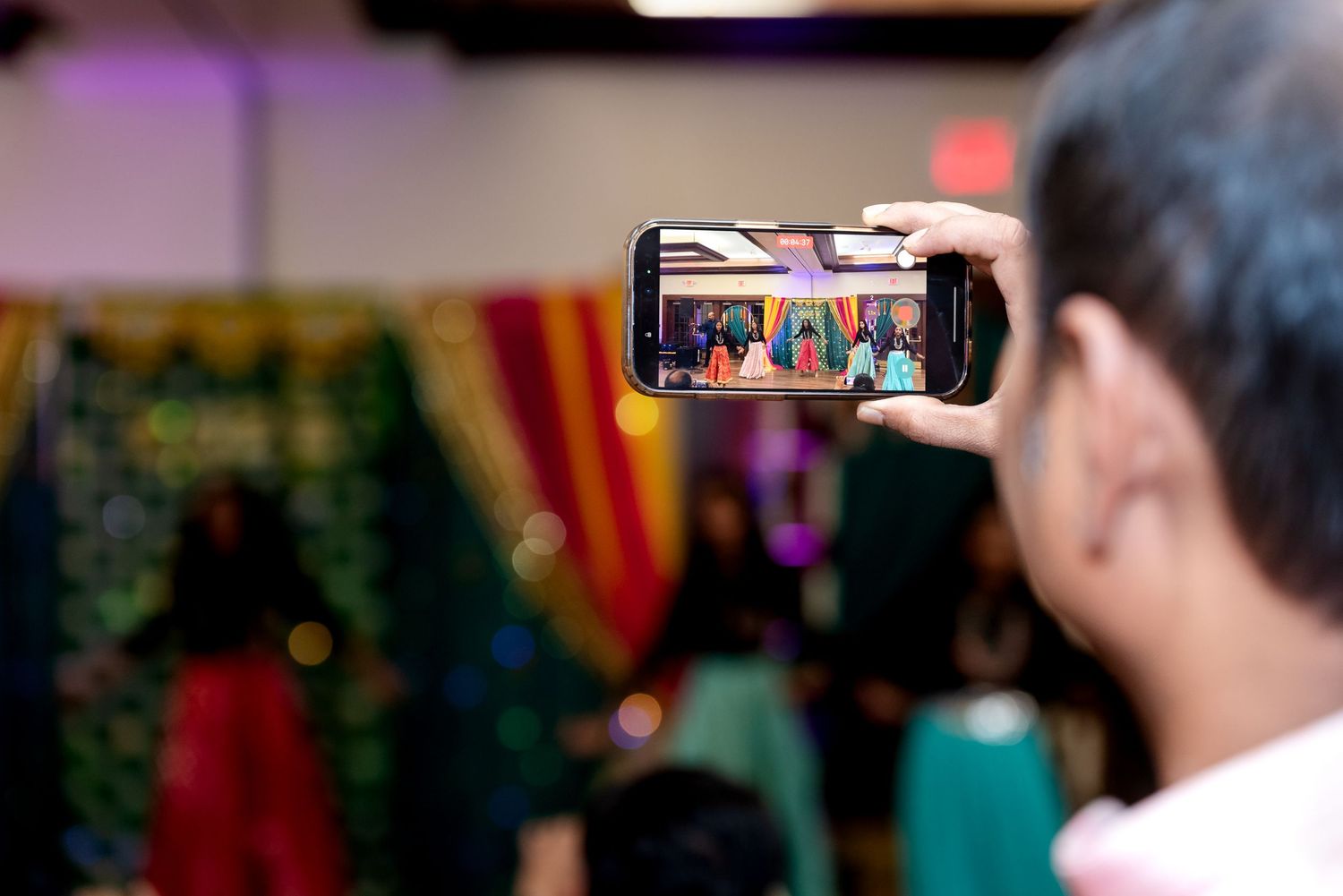 Someone holds up a smartphone to capture a photo at a colorful indoor event.