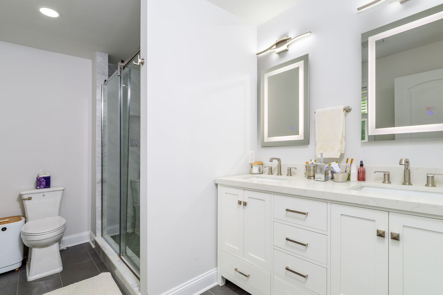 Modern white bathroom with glass shower and double vanity.