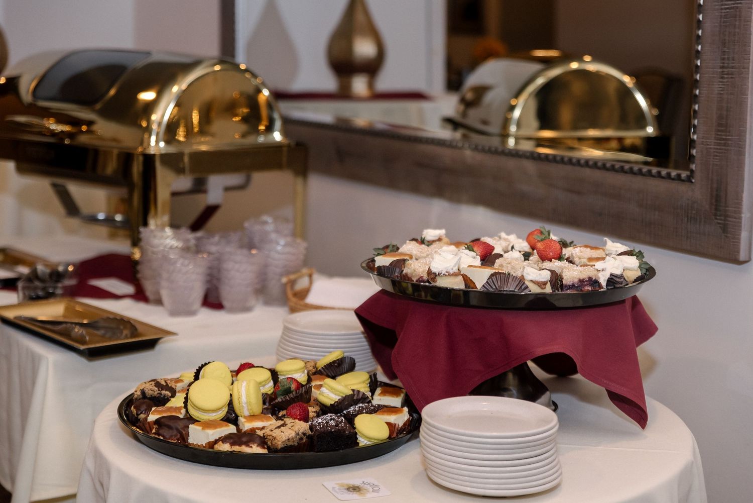 Catering setup with elegant food displays and serving plates at an indoor event.