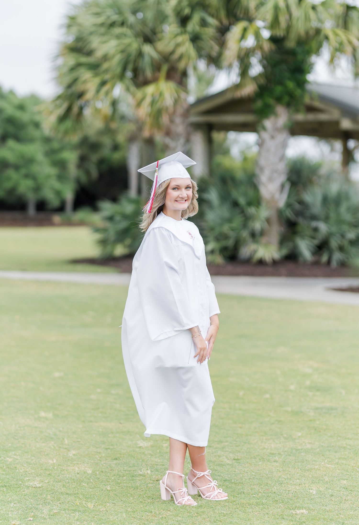 White-clad figure walking gracefully across a lush green lawn with palm trees in the background.