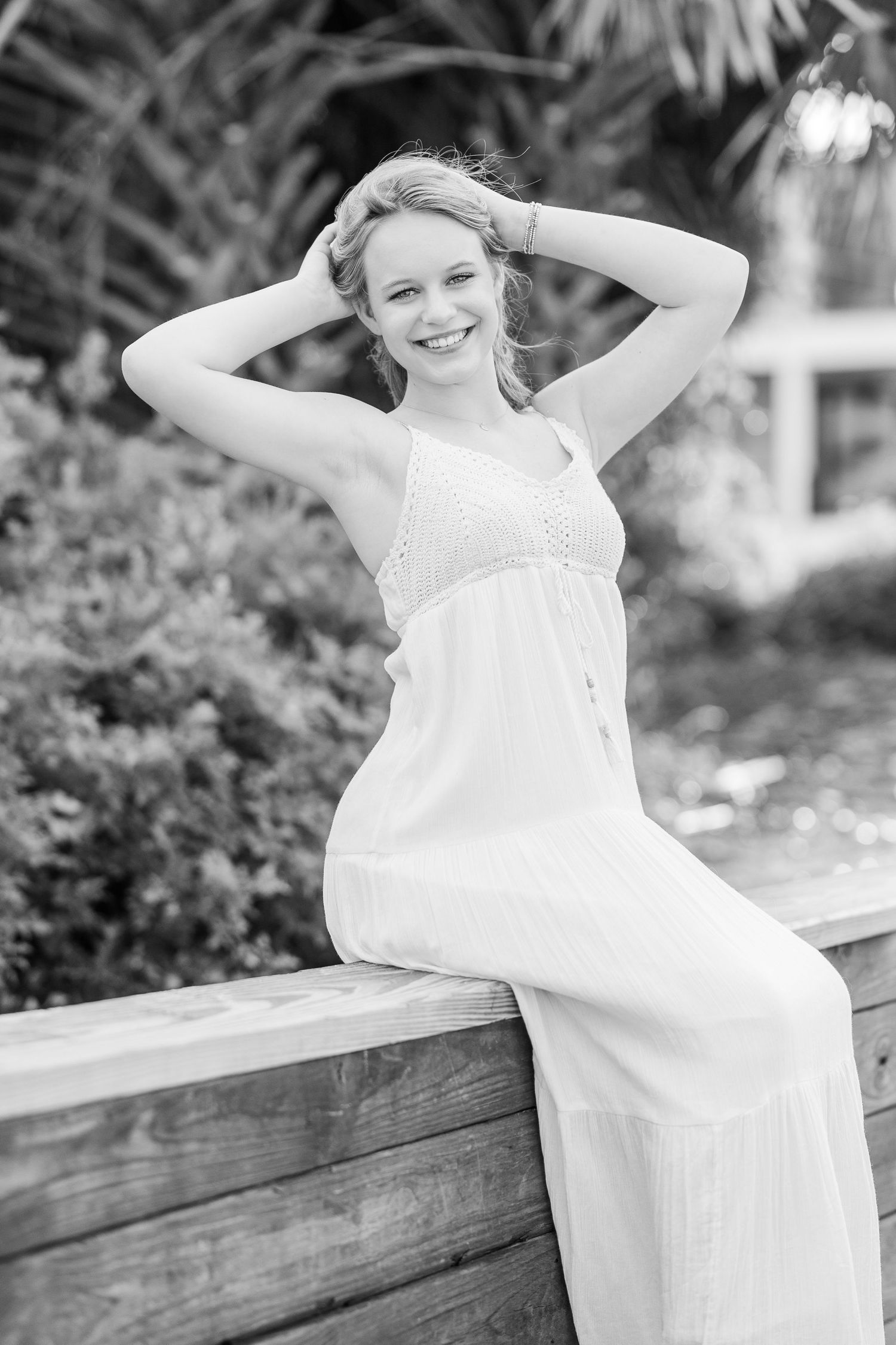 A casual white sundress is featured in a black and white portrait against lush foliage.