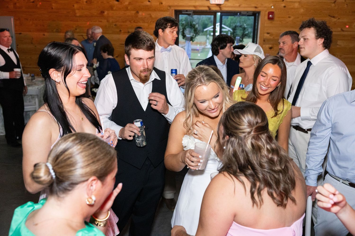 Wedding guests mingle and laugh together during lively barn reception celebration.