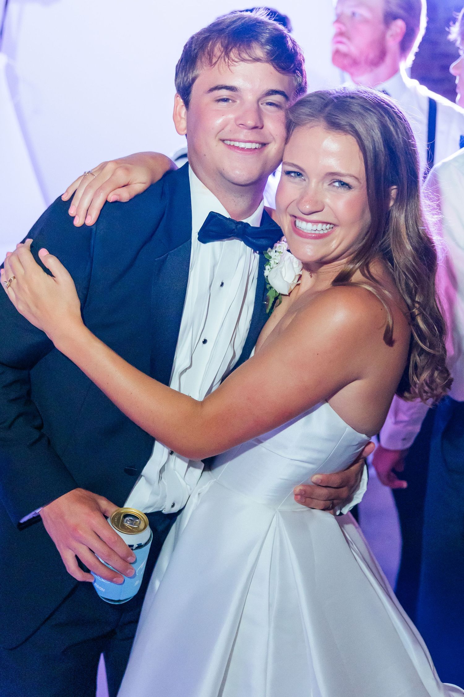 Smiling bride and groom embrace warmly on the dance floor during their festive wedding reception celebration.