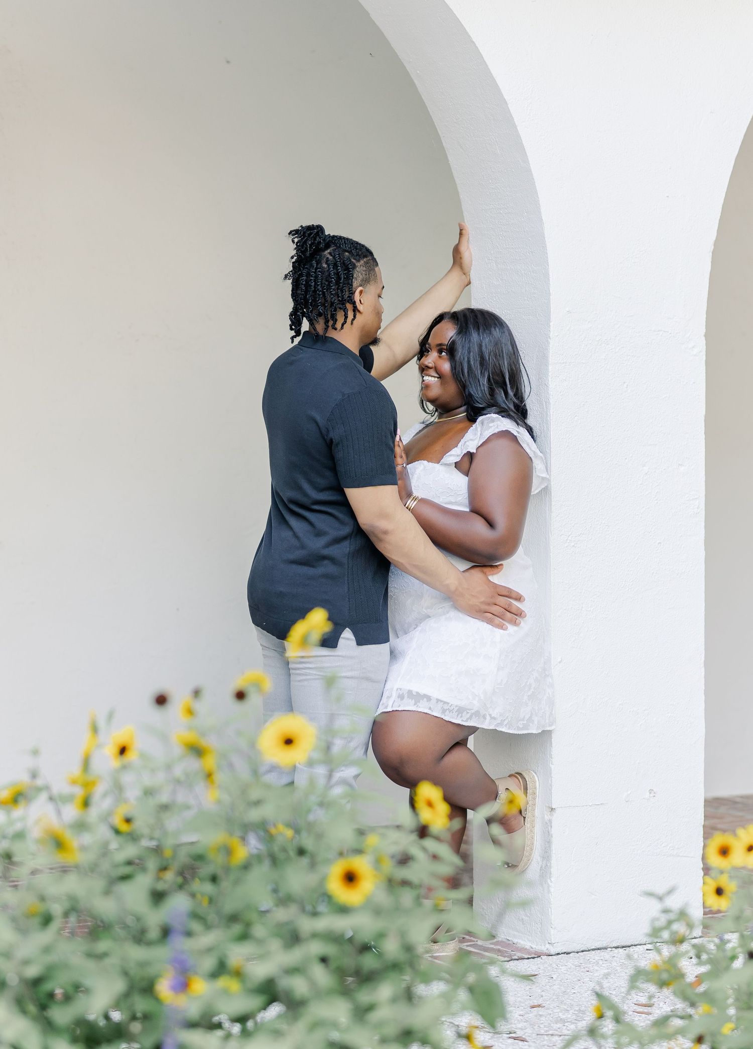 Romantic couple photos against a white archway with yellow sunflowers in the foreground.