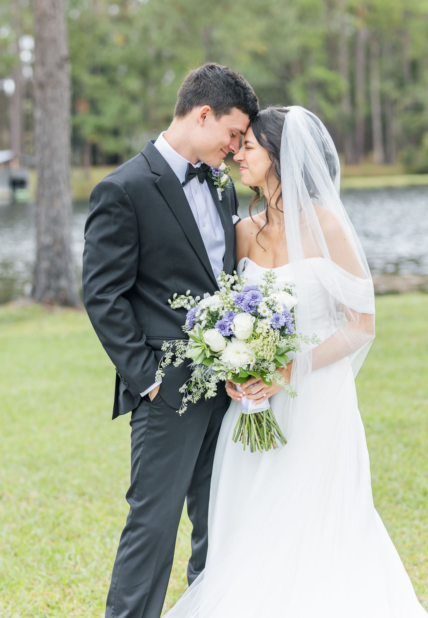 A romantic wedding couple shares intimate moments in a series of outdoor portraits with white and purple florals.