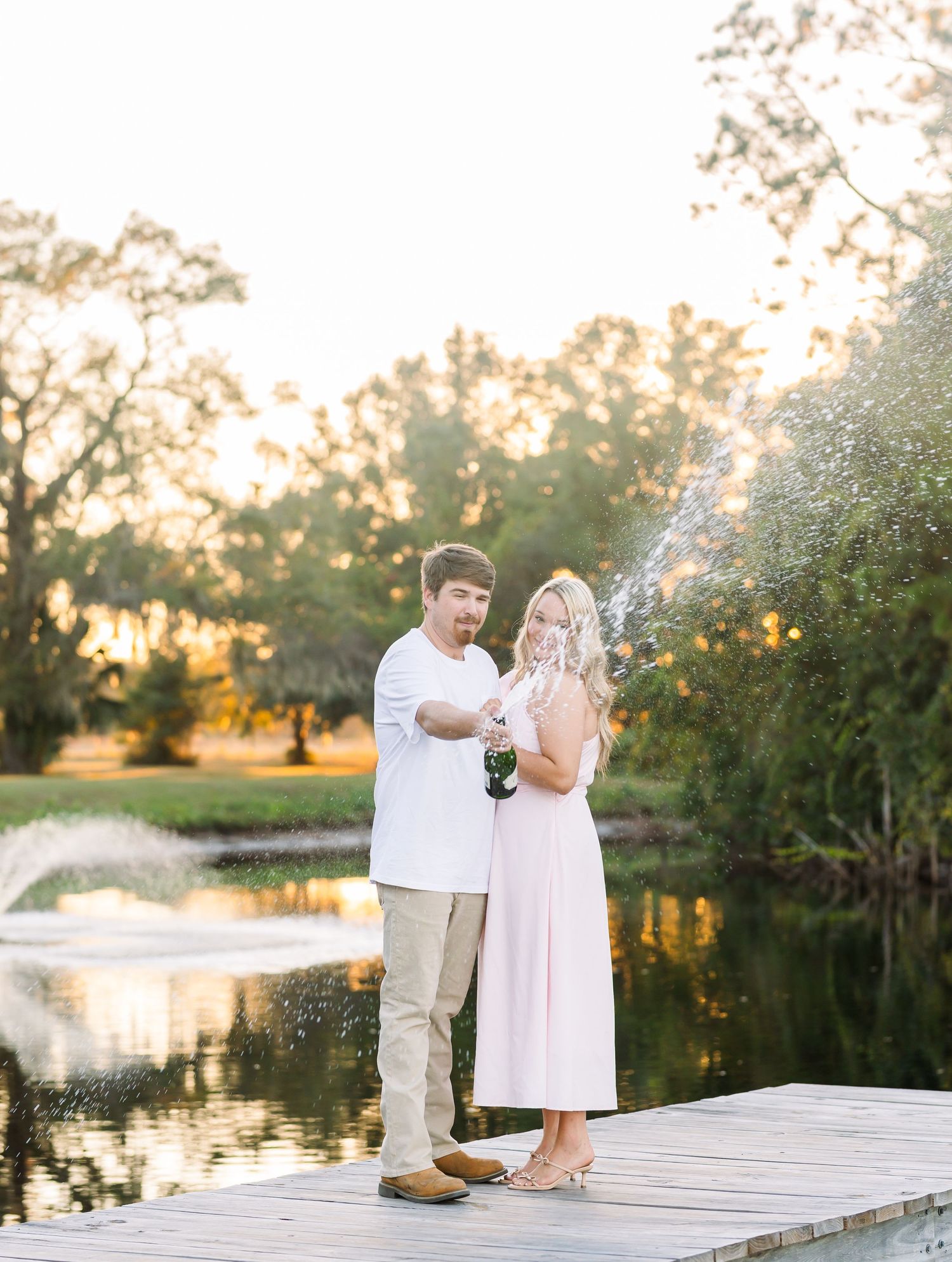 Couple shares romantic moment on lakeside dock during golden hour.