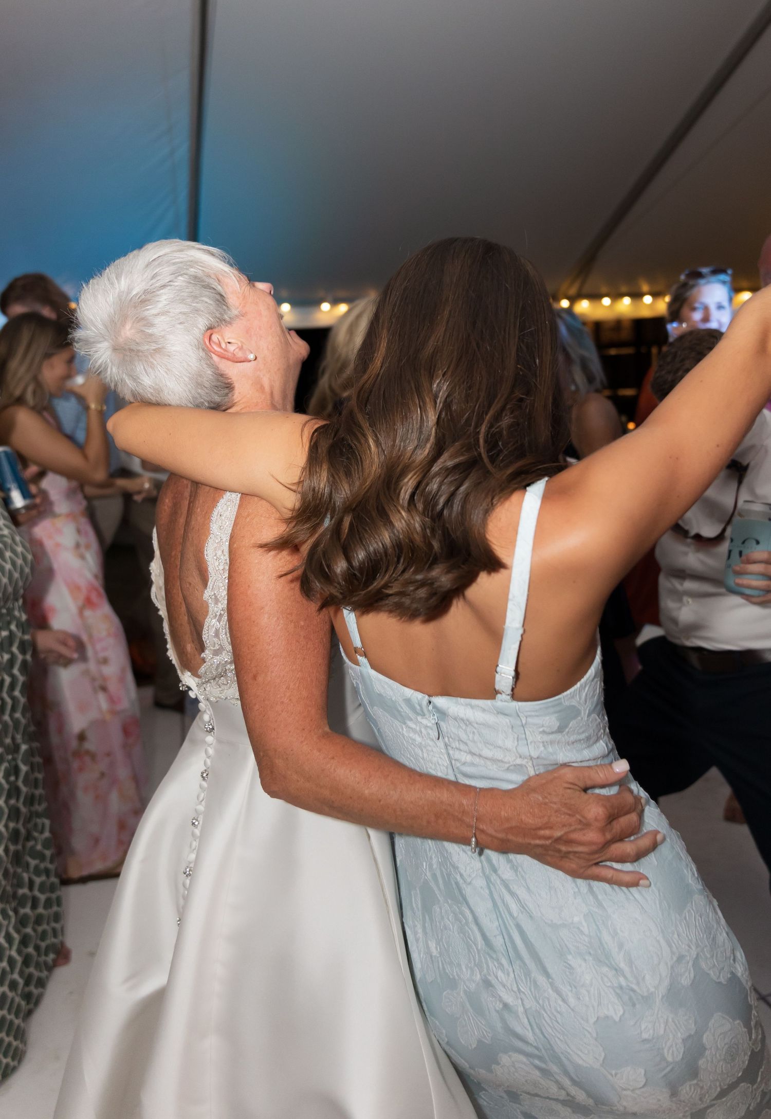 Wedding guests embracing and dancing together during a reception celebration.