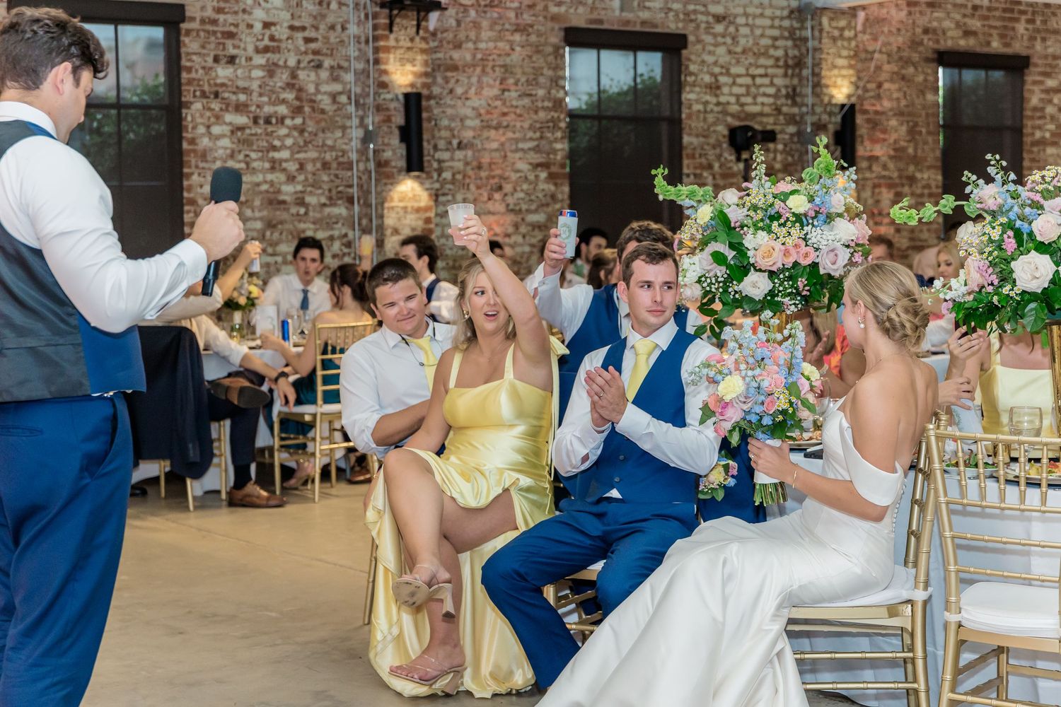 Wedding reception guests enjoy a celebratory moment at a rustic brick venue with elegant floral decor.
