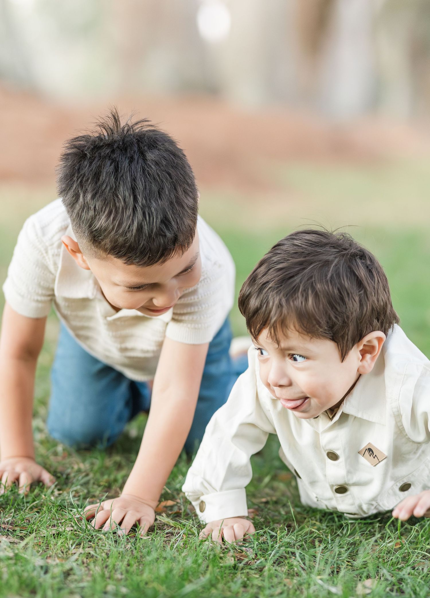 Child crawling playfully on green grass during outdoor photo session.