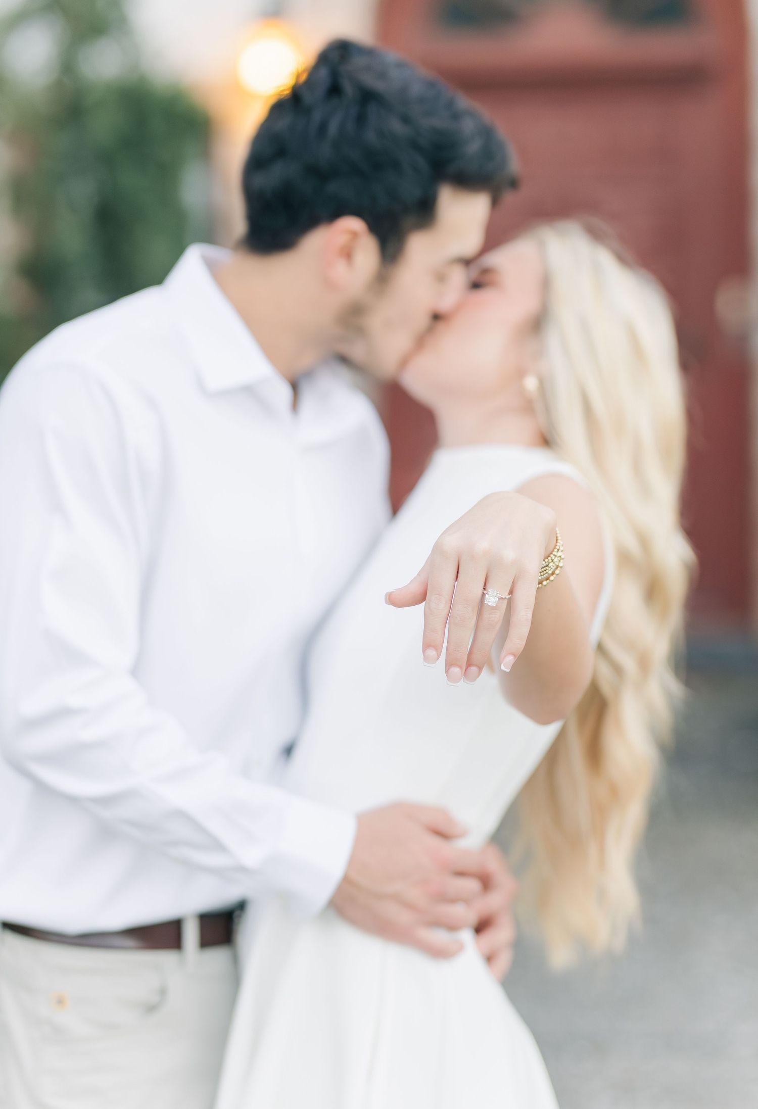 Engagement photo series showing intimate moments in white outfits against a brick wall.