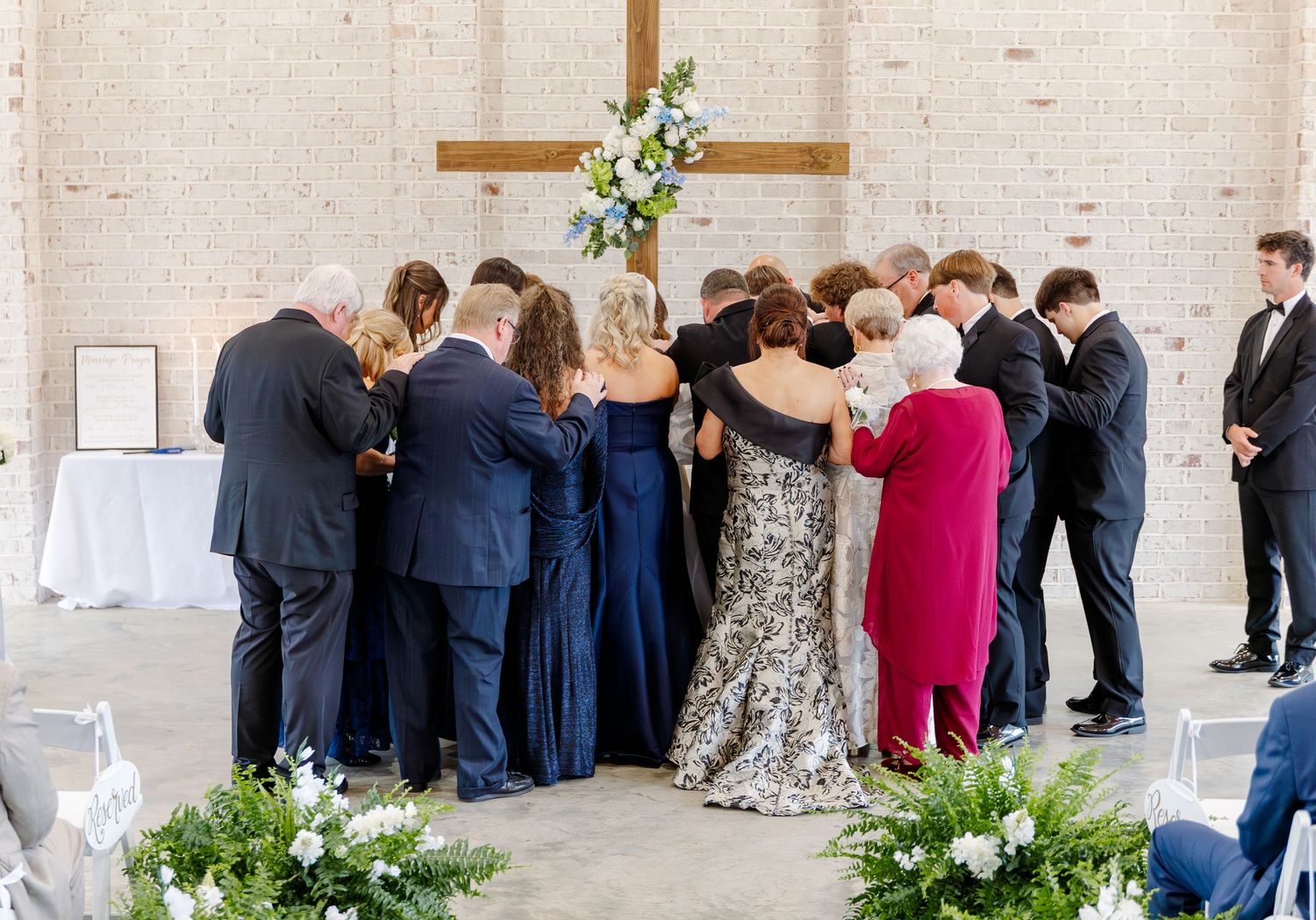 Family gathering in prayer around bride and groom at the wedding altar after ceremony.