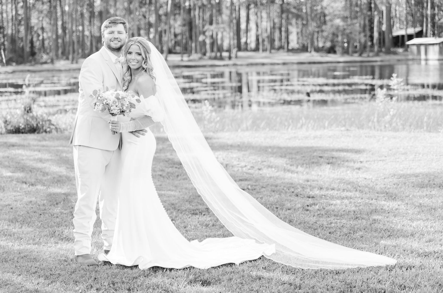 A timeless black and white wedding portrait capturing a tender moment by the water.