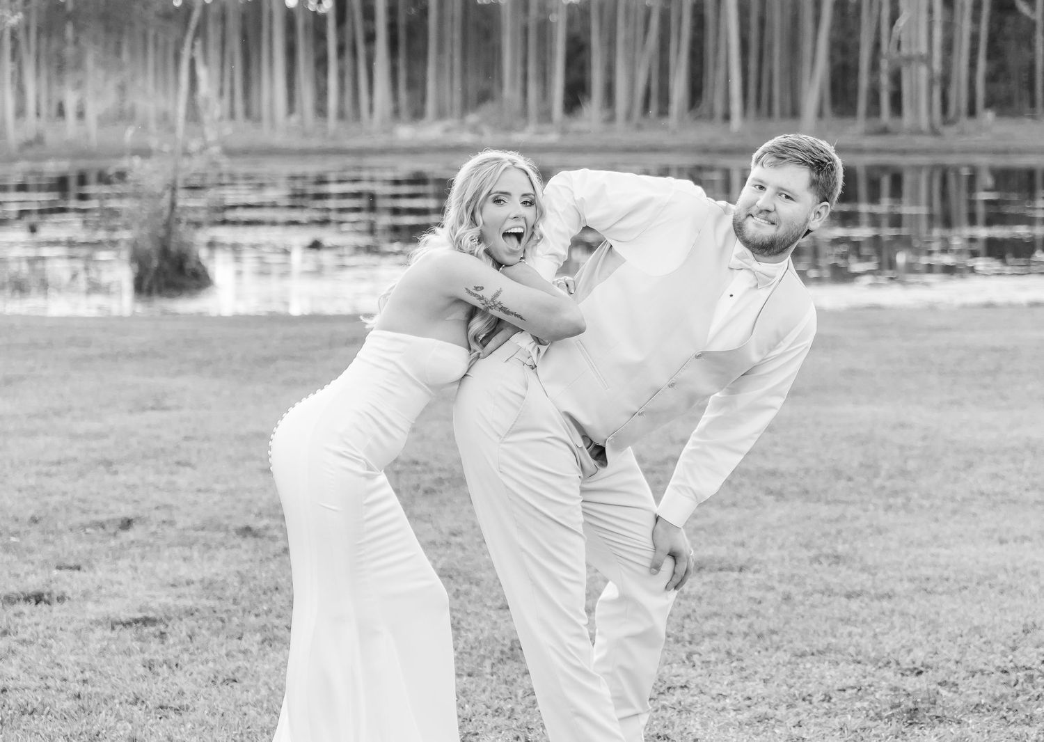 Black and white wedding photo showing couple's fun interaction during outdoor photoshoot.