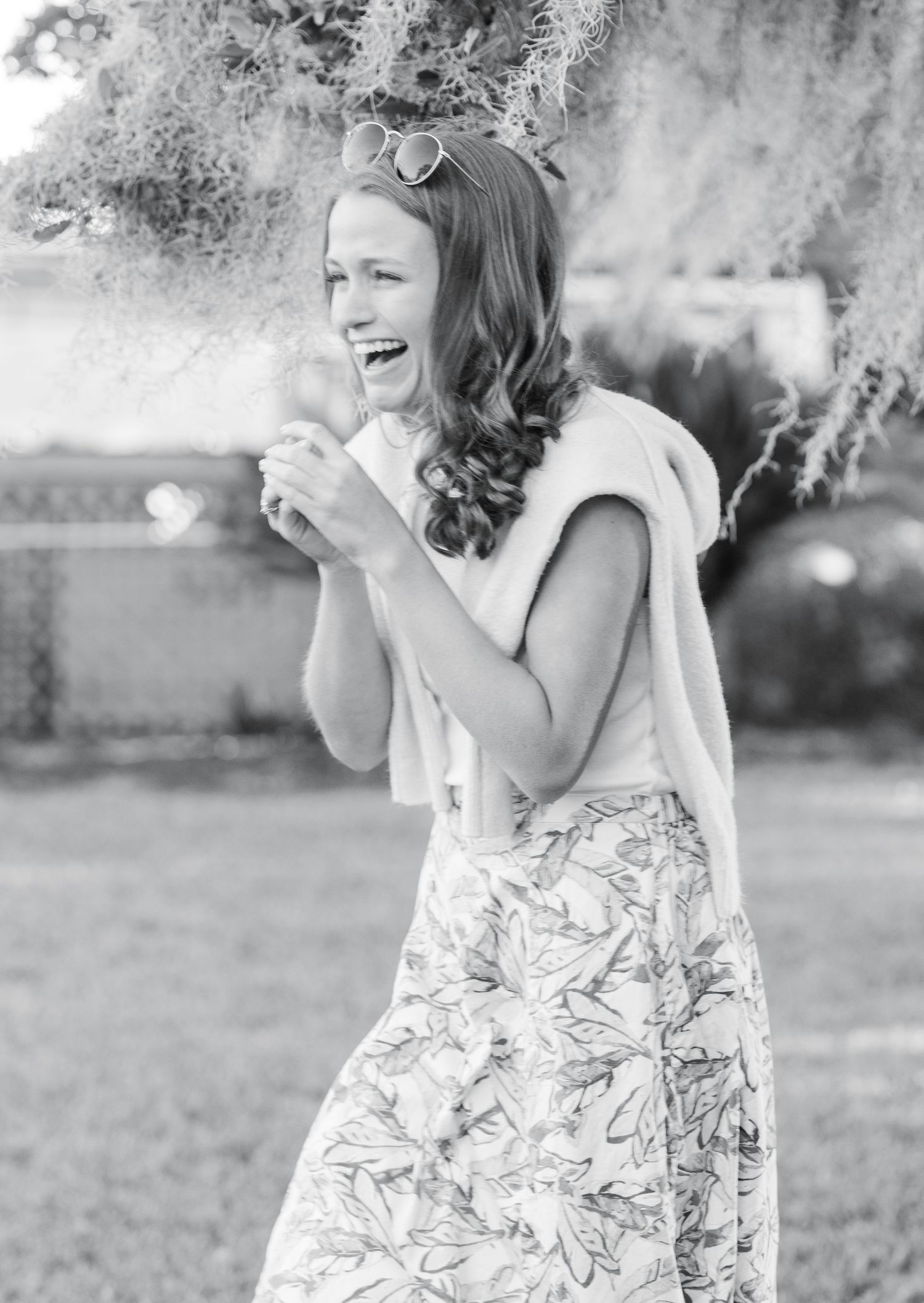 A joyful moment captured in black and white as someone laughs expressively in a floral dress outdoors.