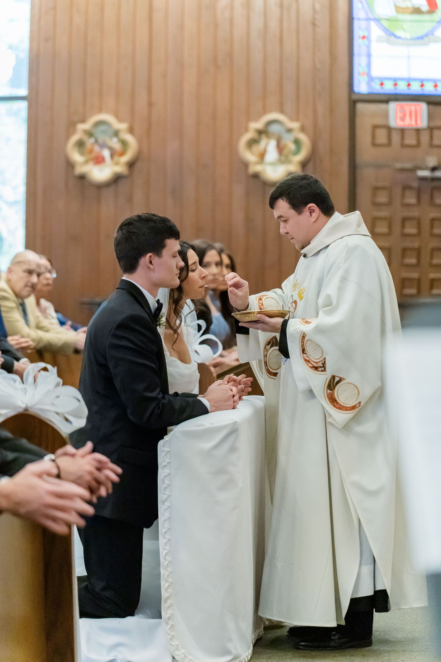 A Catholic priest administers Holy Communion to a parishioner during a church service.