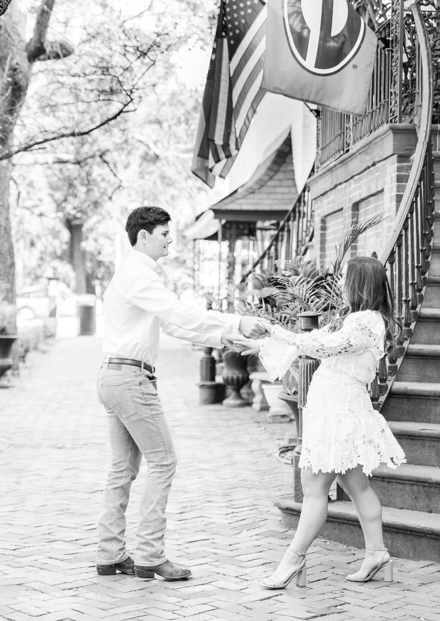 A romantic black and white photo of a couple dancing on a historic brick sidewalk.