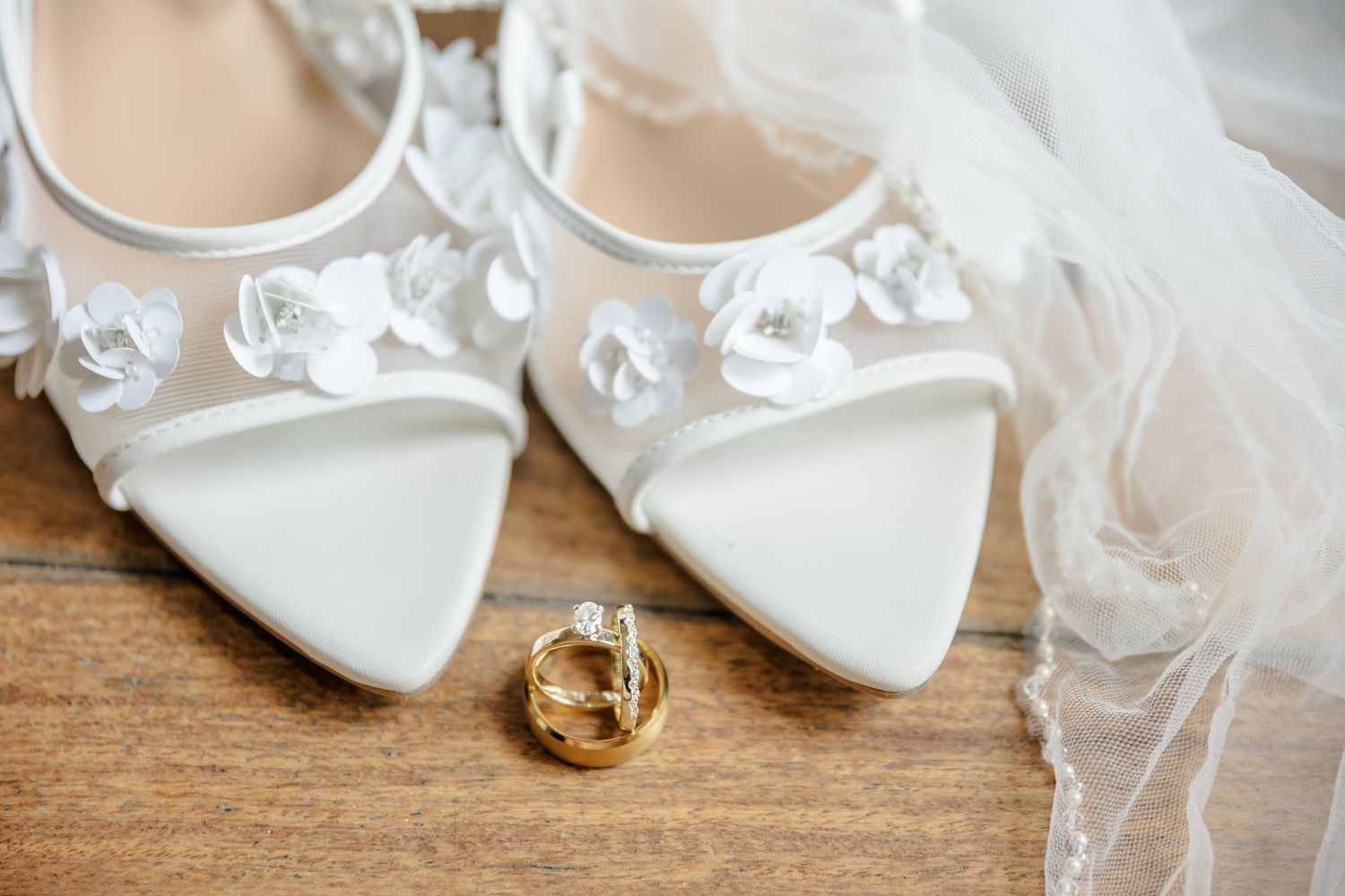 Elegant white satin bridal heels with delicate ribbons and bows arranged in a row.