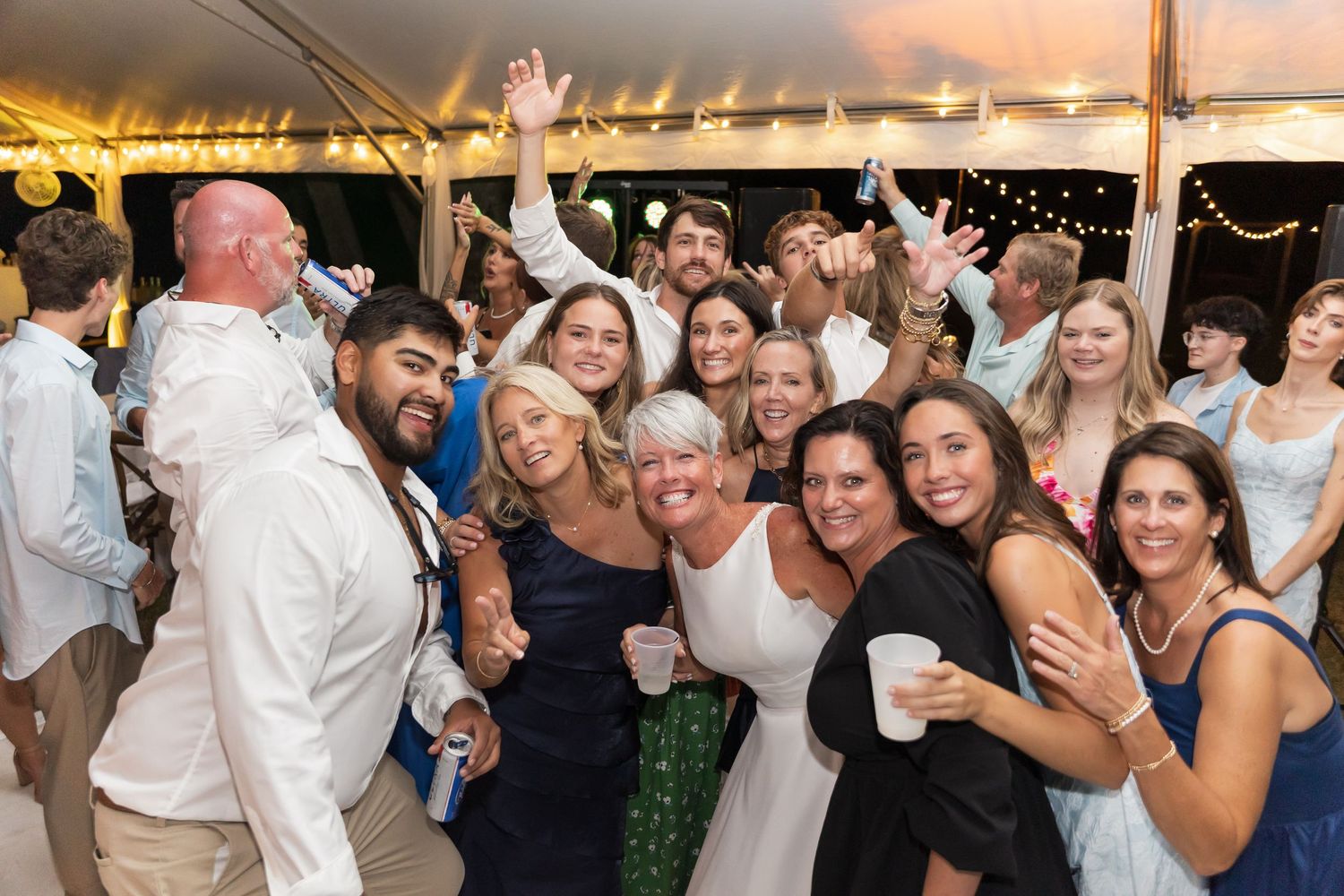 Wedding guests dance and celebrate together on a crowded dance floor during an evening reception party.