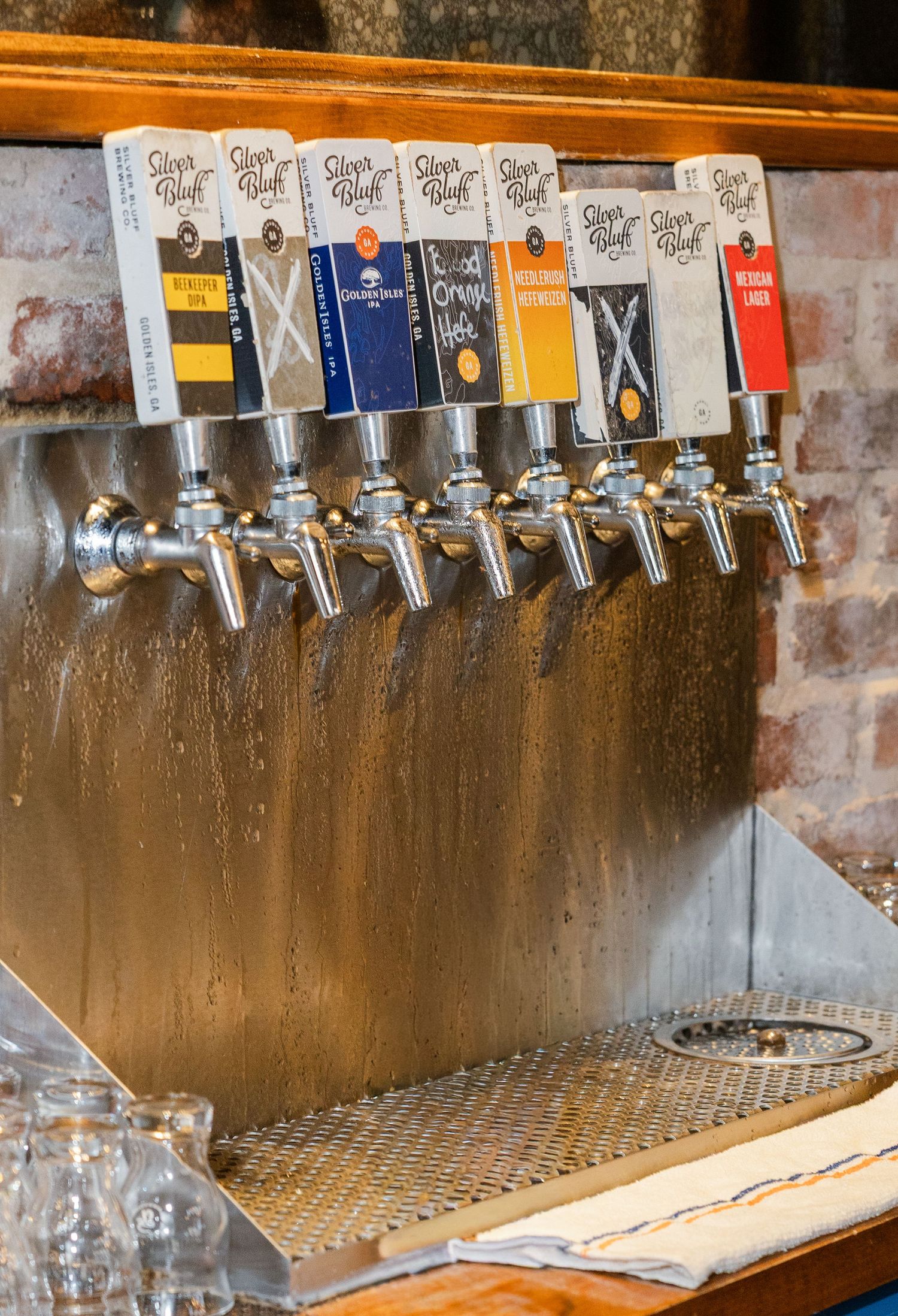 Row of Silver Bluff craft beer tap handles on a stainless steel draft tower at a bar.