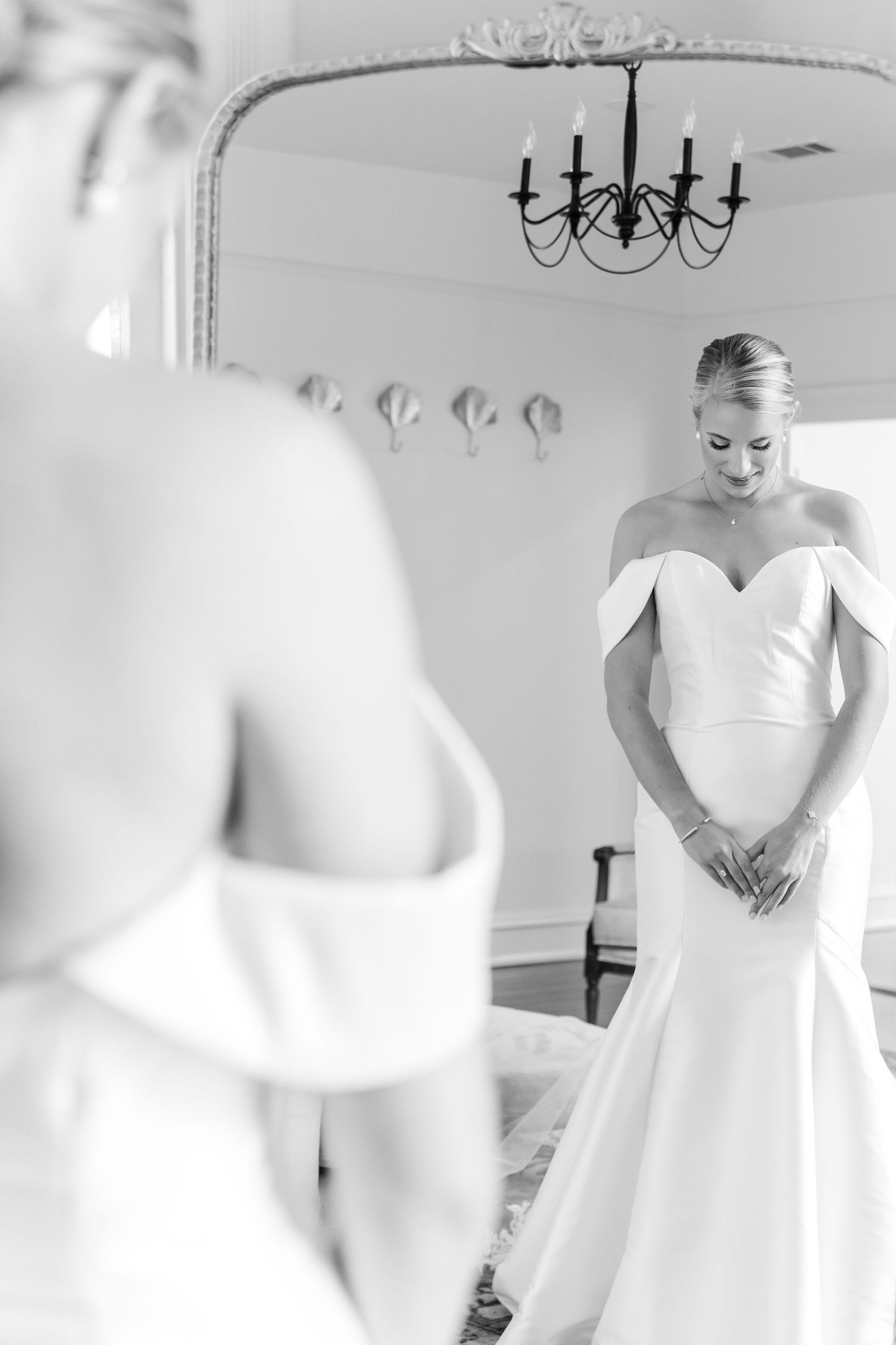 A series of black and white wedding preparation photos showing a bride getting ready in an elegant room with chandeliers.