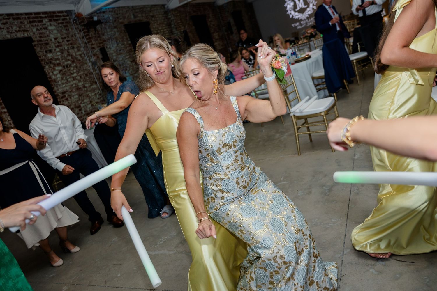 Celebratory dancing at a wedding reception with guests in formal attire and pastel dresses.