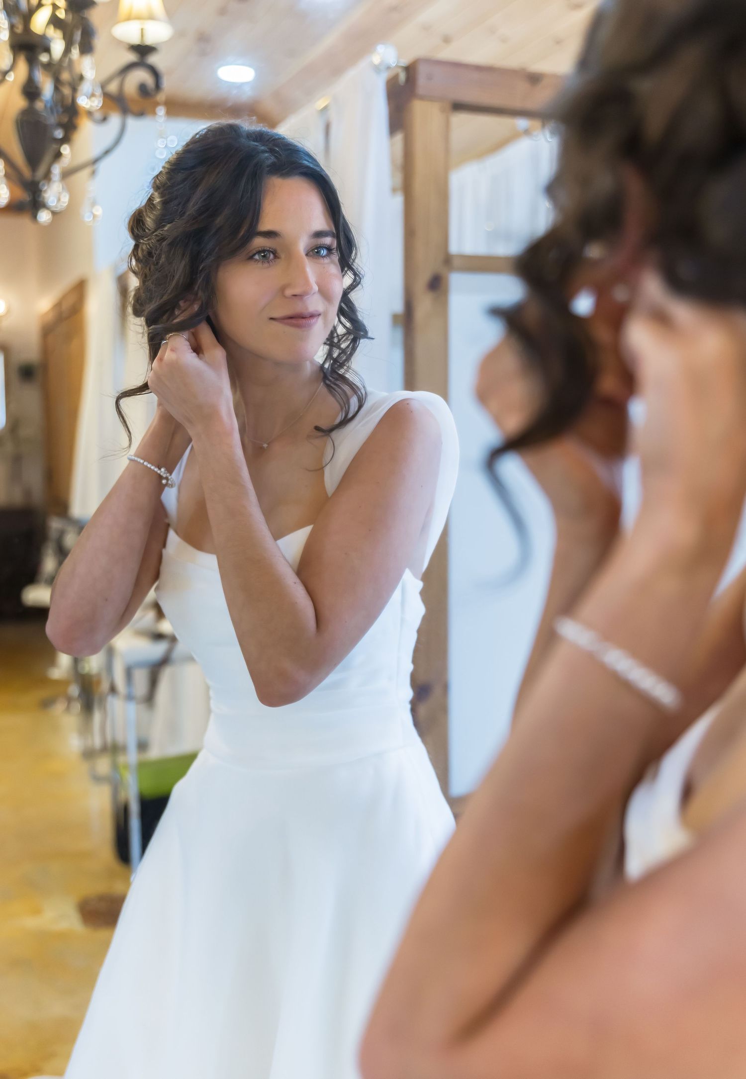 A person in a white dress applies makeup in a brightly lit room with elegant decor.
