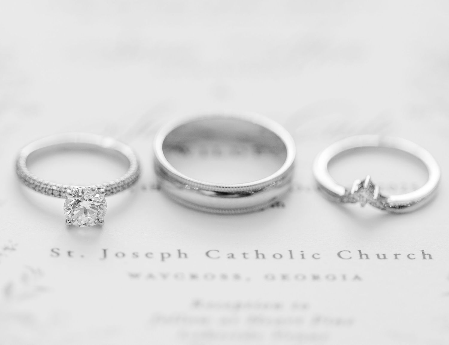 Three wedding rings photographed in black and white on a church document from St. Joseph Catholic Church.
