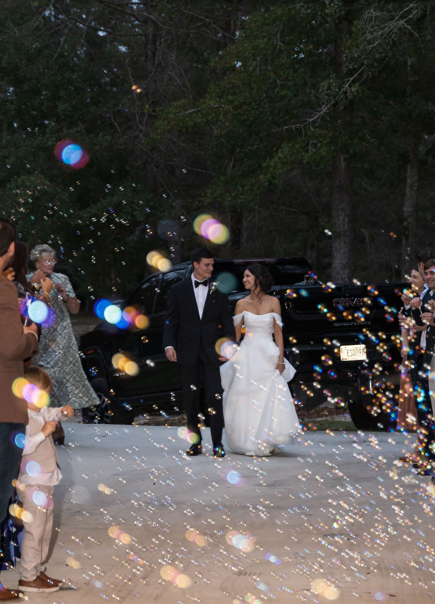 Wedding celebration at night with magical bokeh lights and bubbles creating a dreamy outdoor atmosphere.