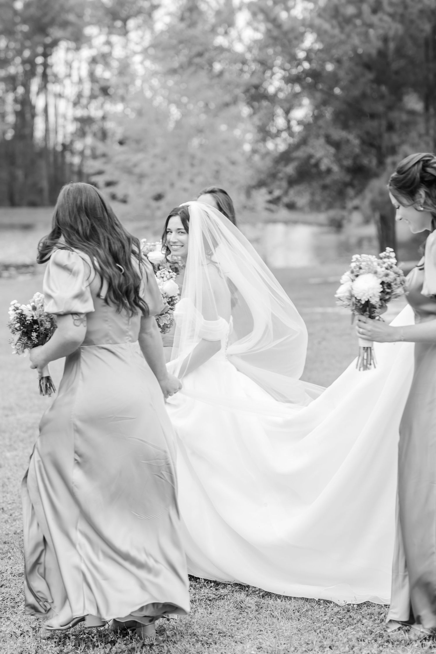Black and white photo series showing bridesmaids in flowing dresses helping arrange the bride's wedding dress train.