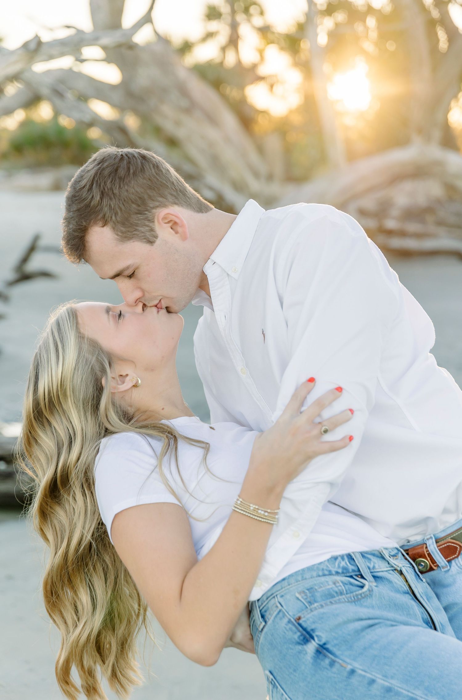 Intimate moment between couple sharing a romantic kiss on the beach at sunset.