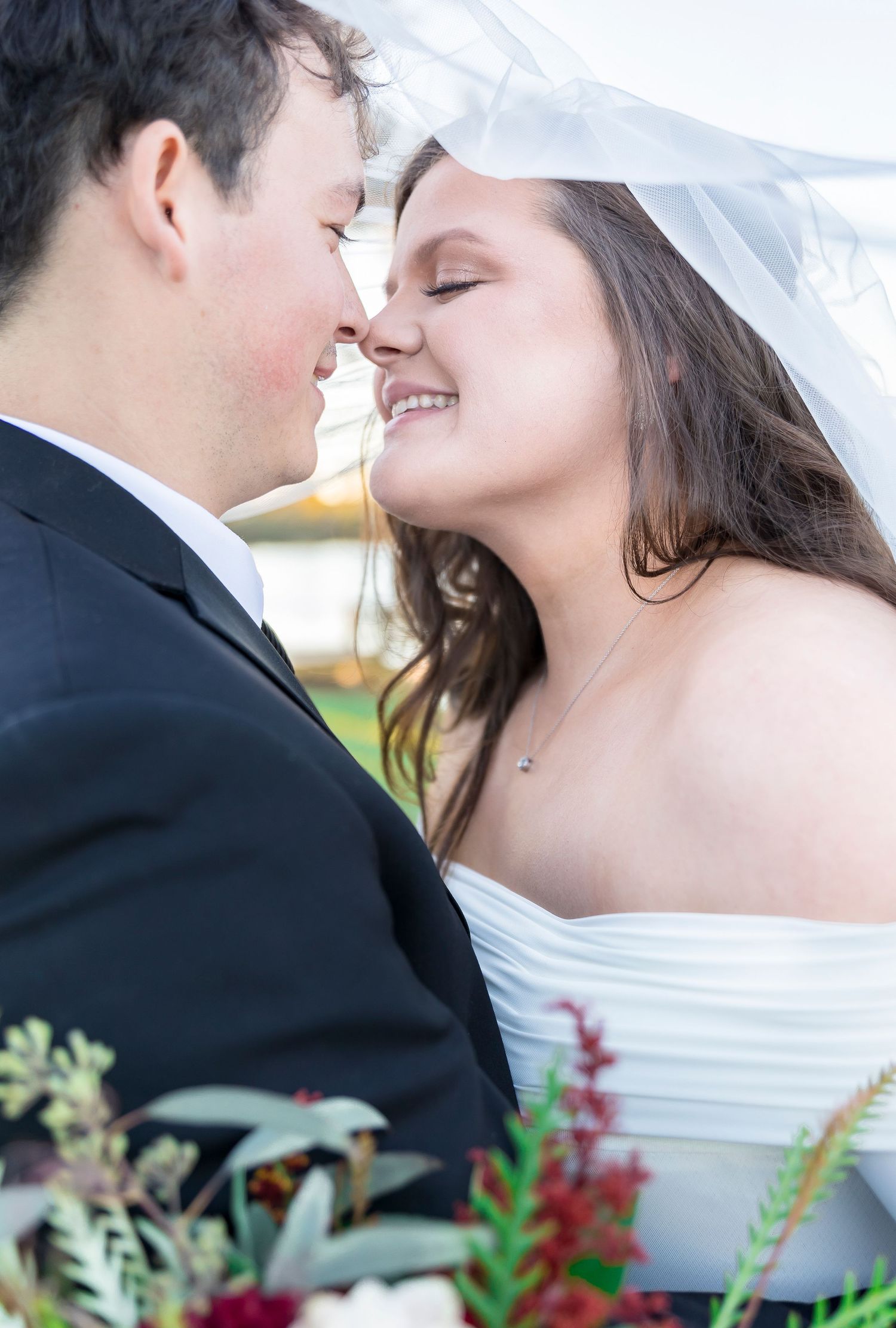 Intimate close-up portrait of newlyweds sharing a tender moment under a flowing veil.