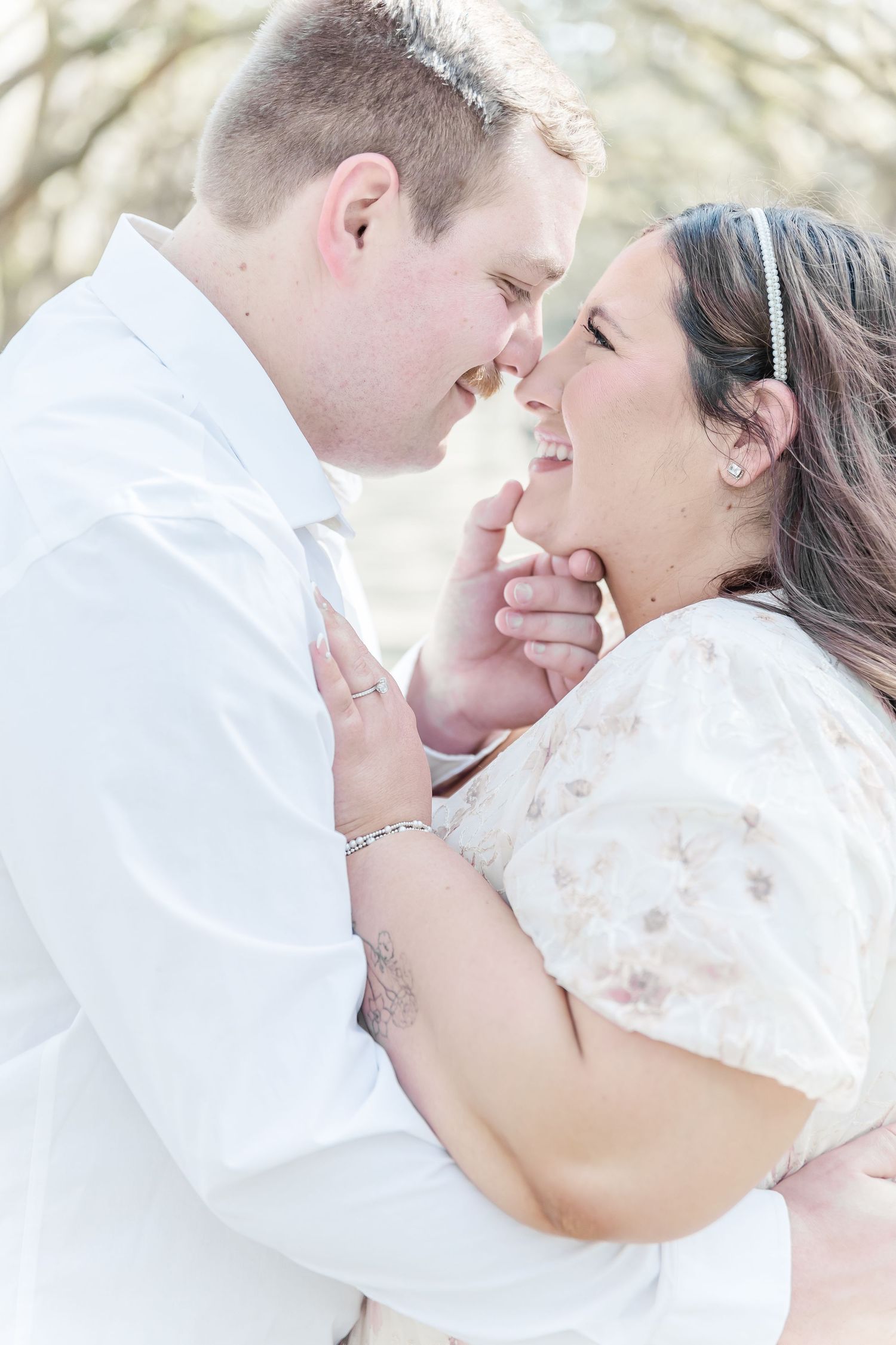 Romantic close-up of couple sharing a tender moment under tree branches.