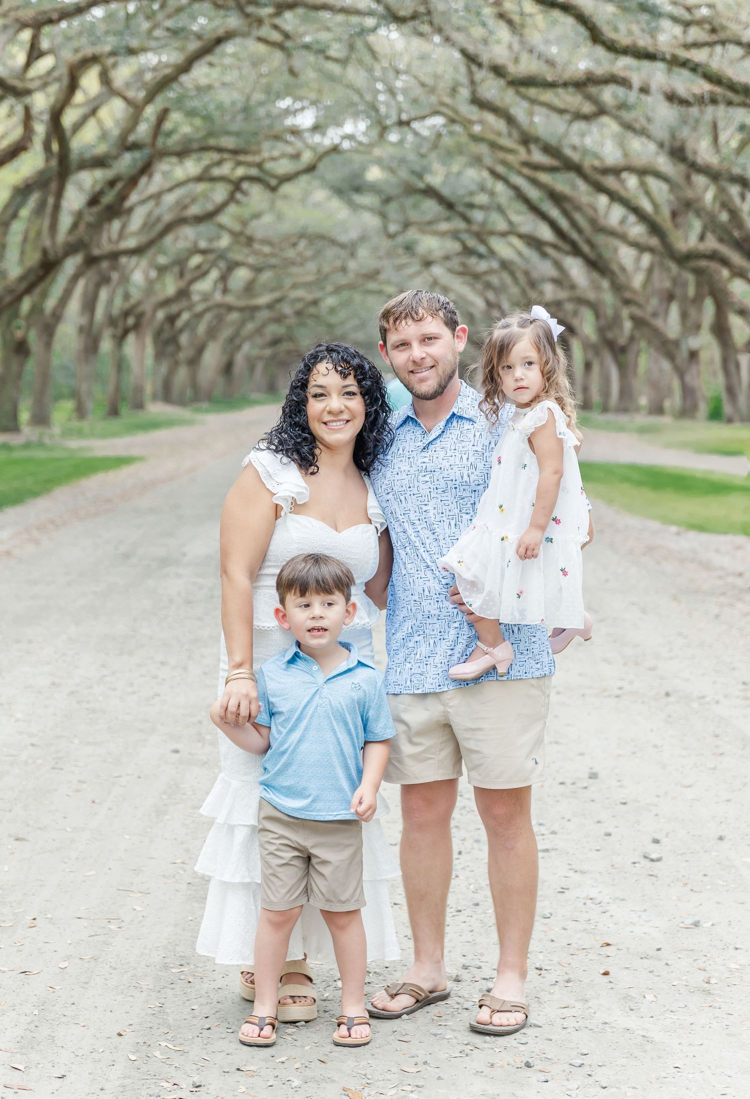 Happy family photo under majestic oak tree canopy on spring day.